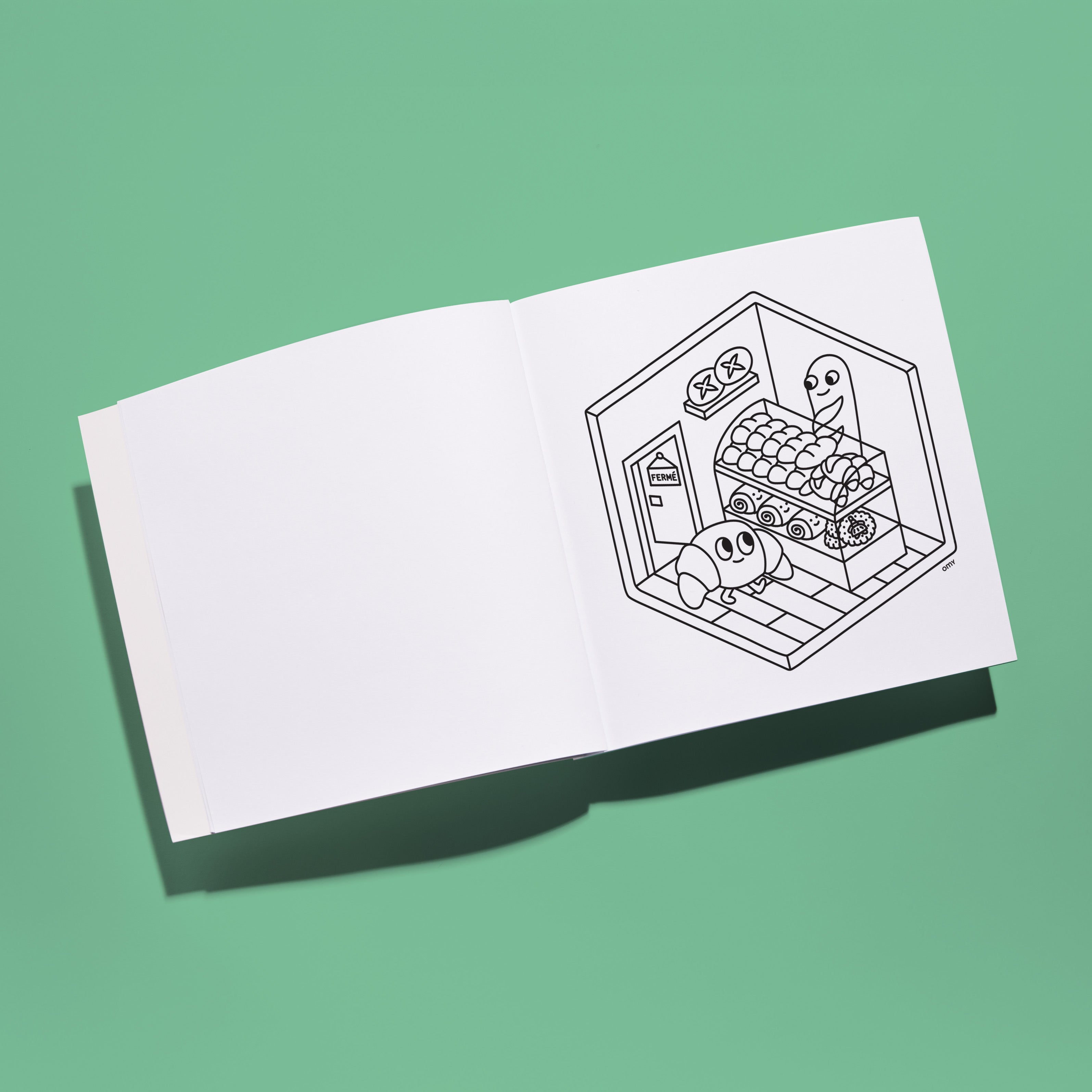 Interior view of Cozy Art Paris coloring book featuring a blank page and an illustrated 3D Parisian kitchen scene with cute characters, displayed on a green background.