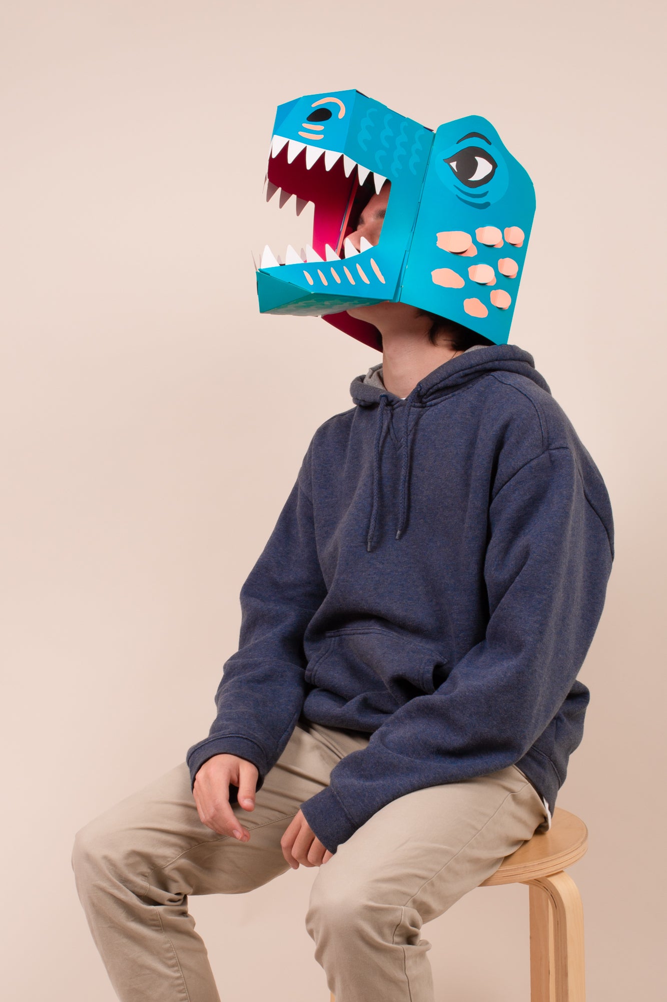 Child wearing the Mask Dino OMY Rex mask sitting on a stool