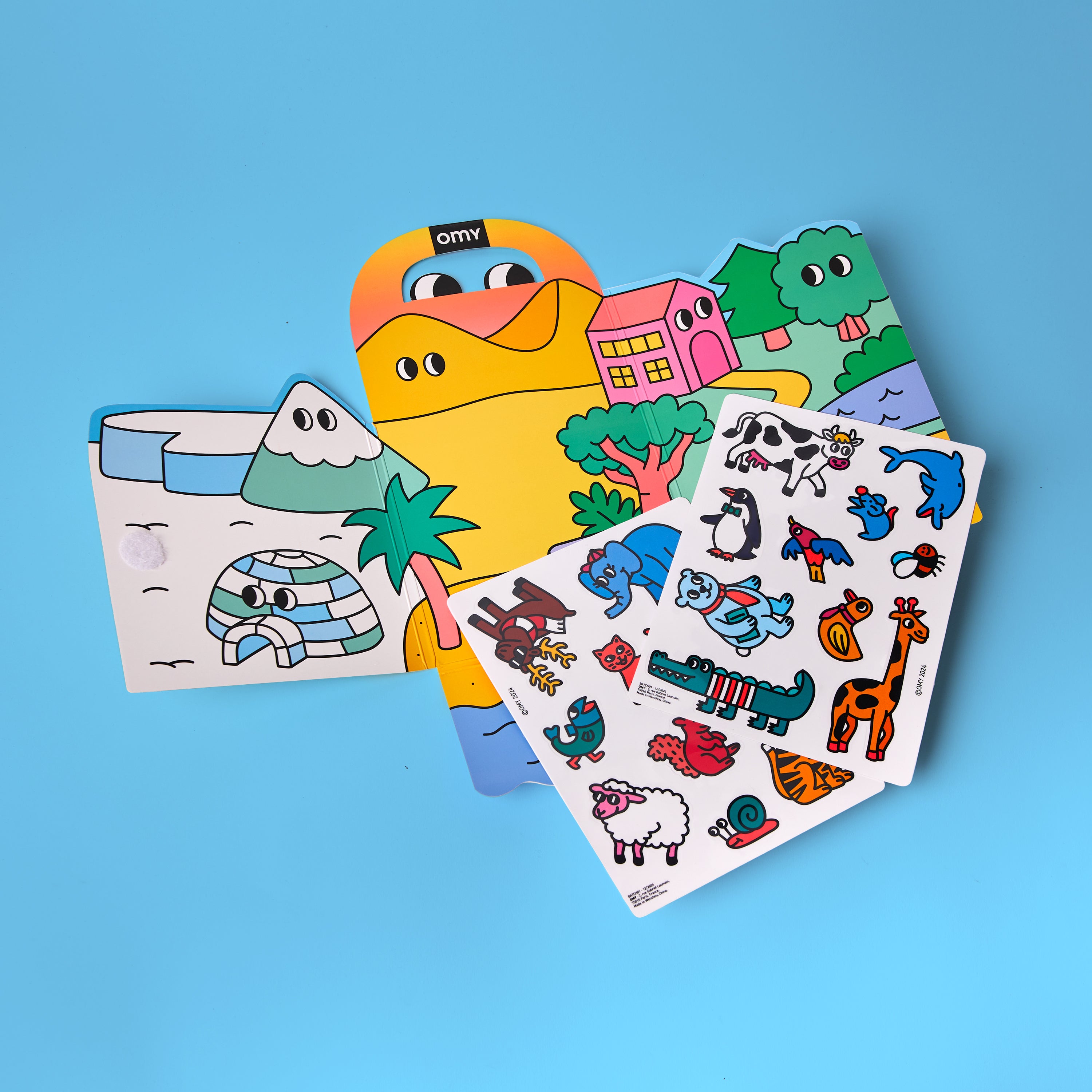 Montessori sticker kit contents displayed with colorful fold-out scenes and silicone animal sticker sheets on blue background.