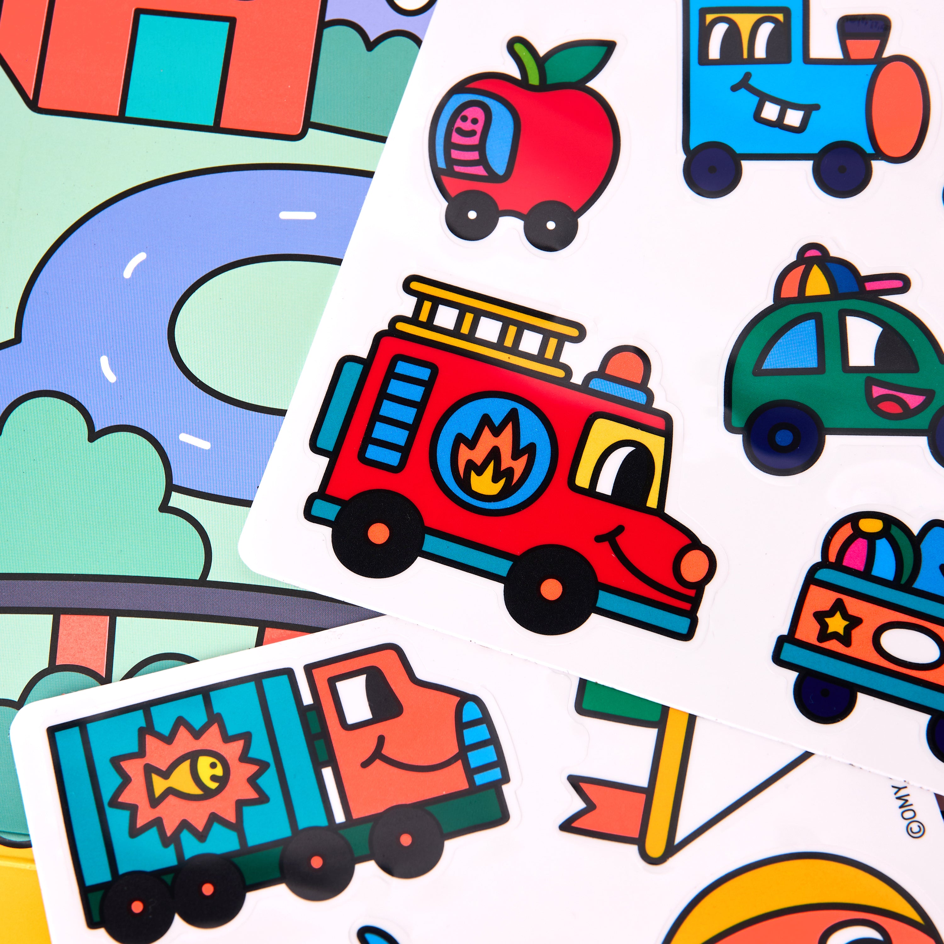 Reusable silicone sticker sheets from OMY Montessori Stickers Kit – Vroom Vroom edition featuring colorful vehicles like firetruck, apple car, train, police car, and gift truck; repositionable stickers for kids aged 3–7