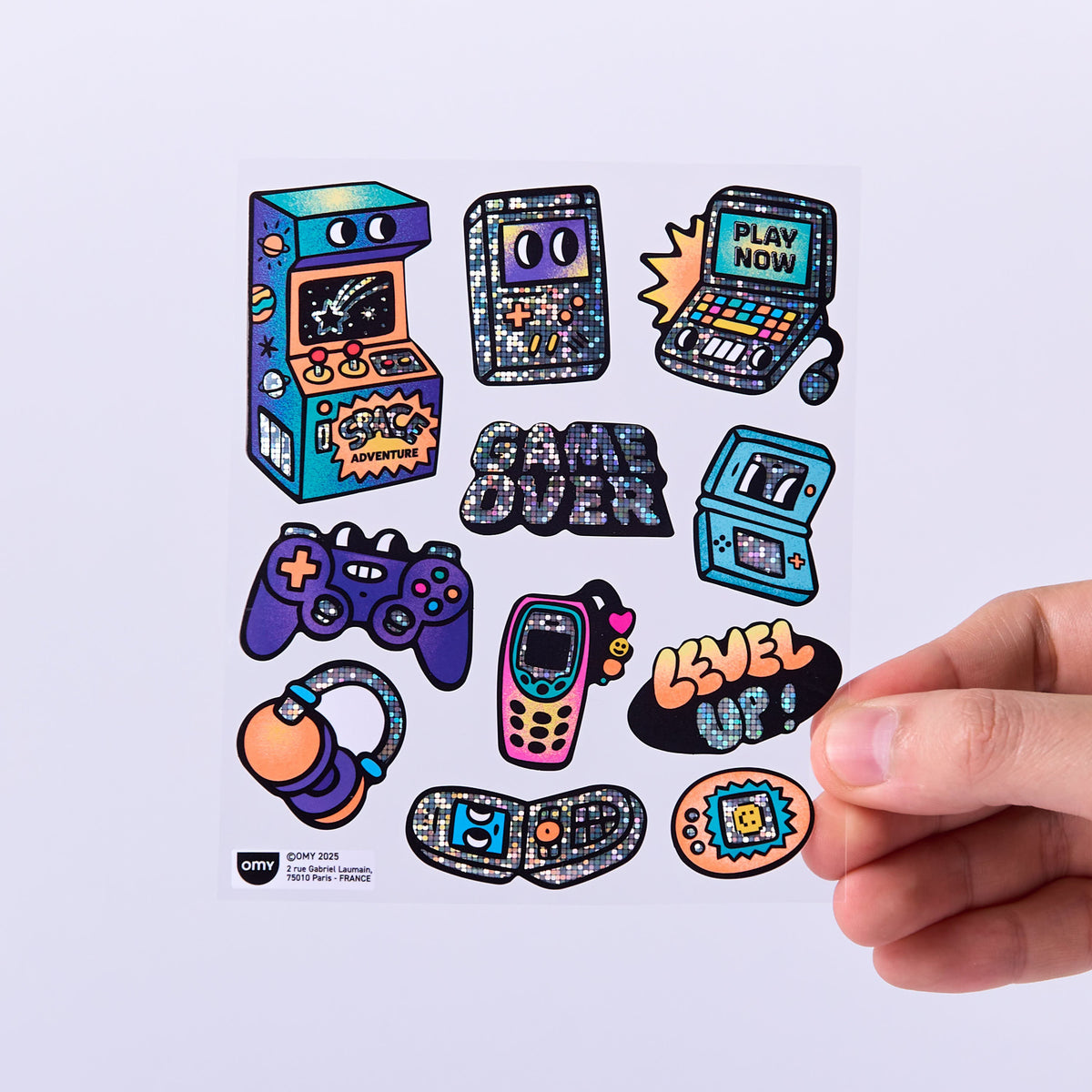 game boy themed stickers OMY on a white background with a hand holding one of them.
