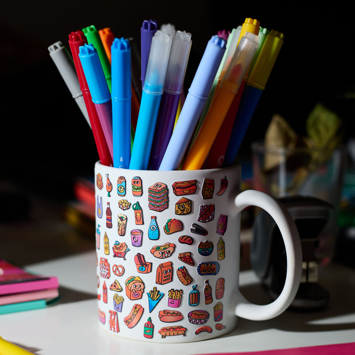 White mug with colorful markers and fabulous stickers on a desk