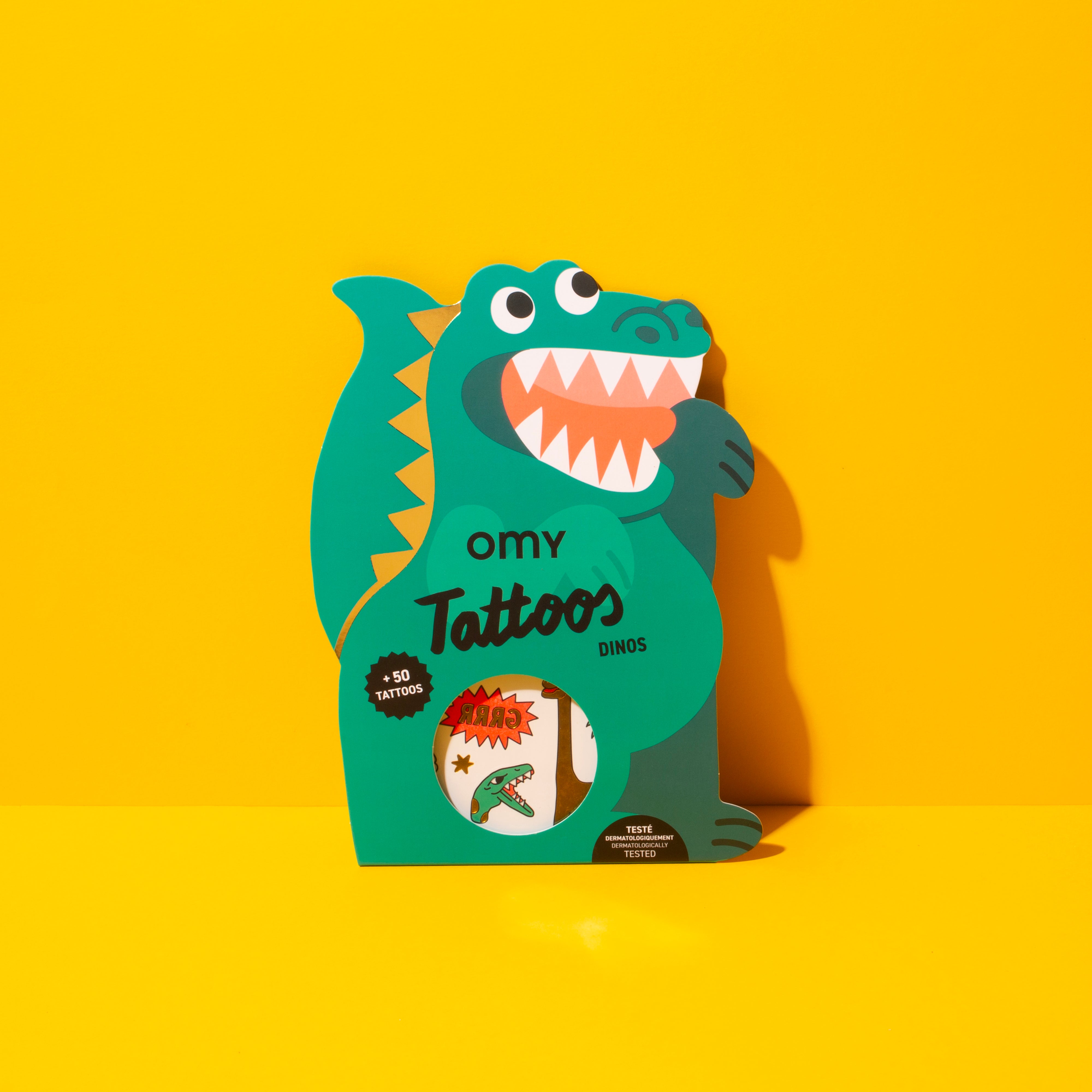 Omy Tattoos Dinos packaging with a dinosaur design on a yellow background