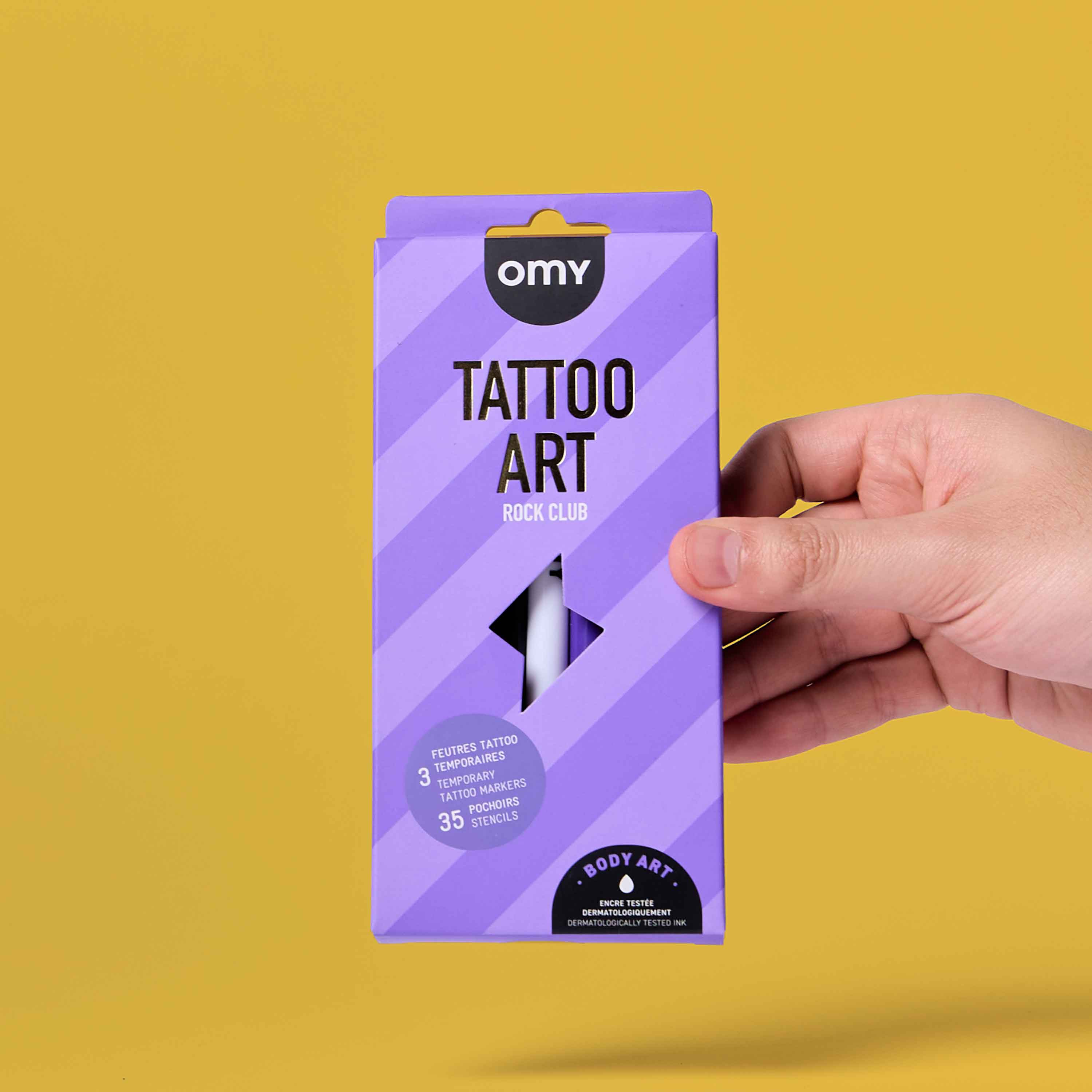 OMY Tattoo Art Rock Club temporary tattoo markers kit packaging held in hand on yellow background