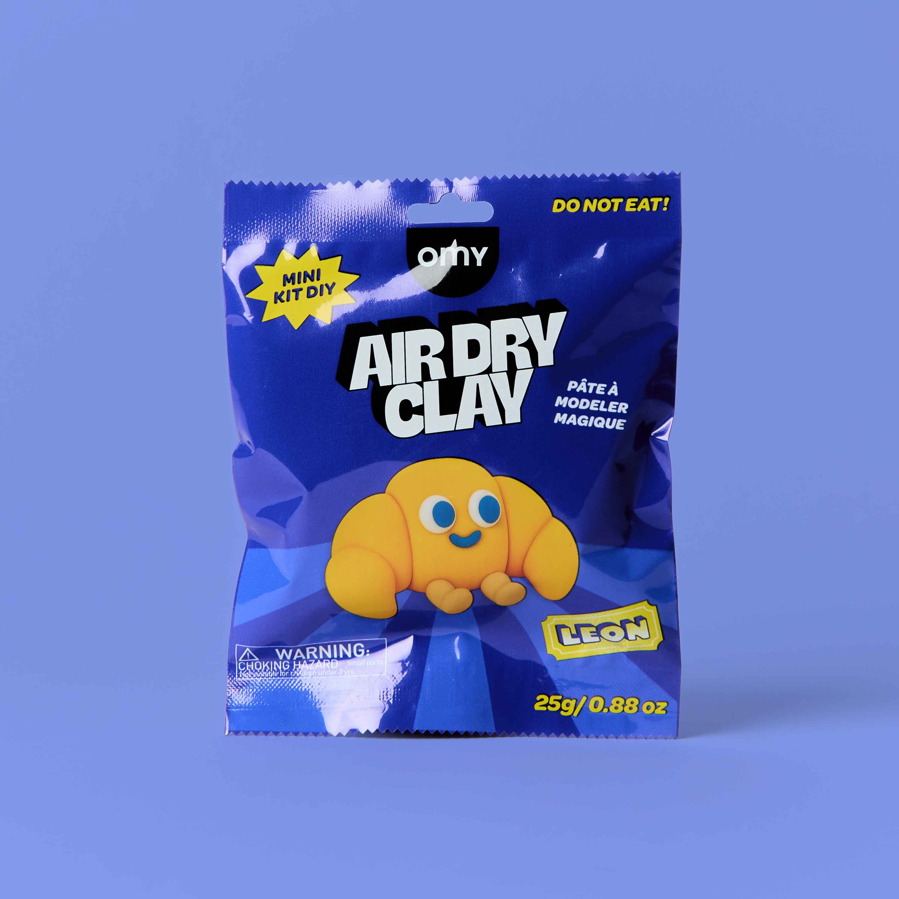 OMY Air Dry Clay Leon mini DIY kit – kawaii croissant character sculpting clay in blue packaging, 25g air dry modeling clay kit for kids on purple background