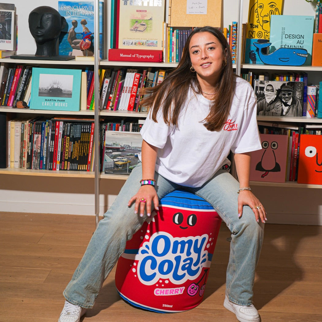 Person sitting on a colorful stool with Omy Cola air pillow
