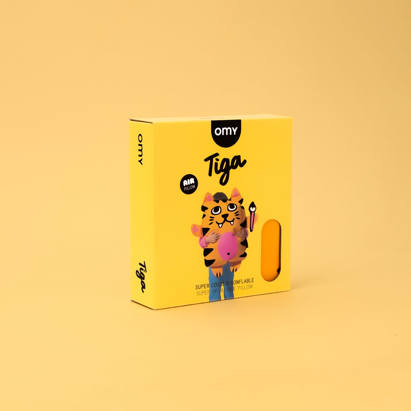 Yellow OMY Tiga inflatable tiger pillow packaging with cartoon tiger illustration on a soft beige background.