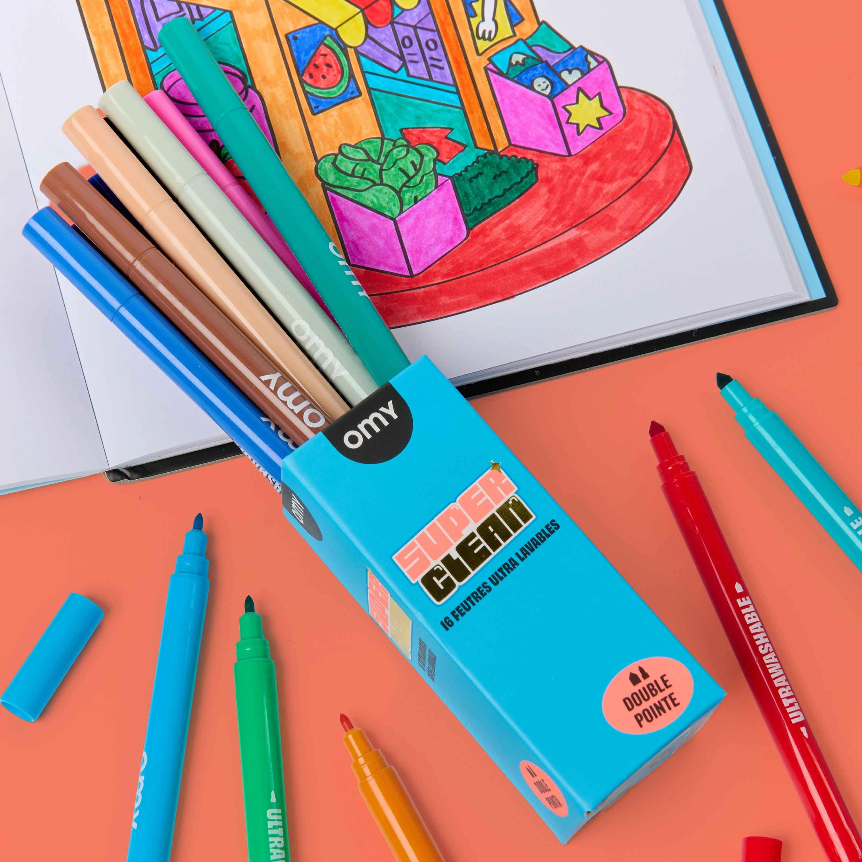 OMY Super Clean 16 ultra-washable dual-tip markers in teal packaging surrounded by colorful felt tip pens on coral background, with a completed kawaii market coloring page