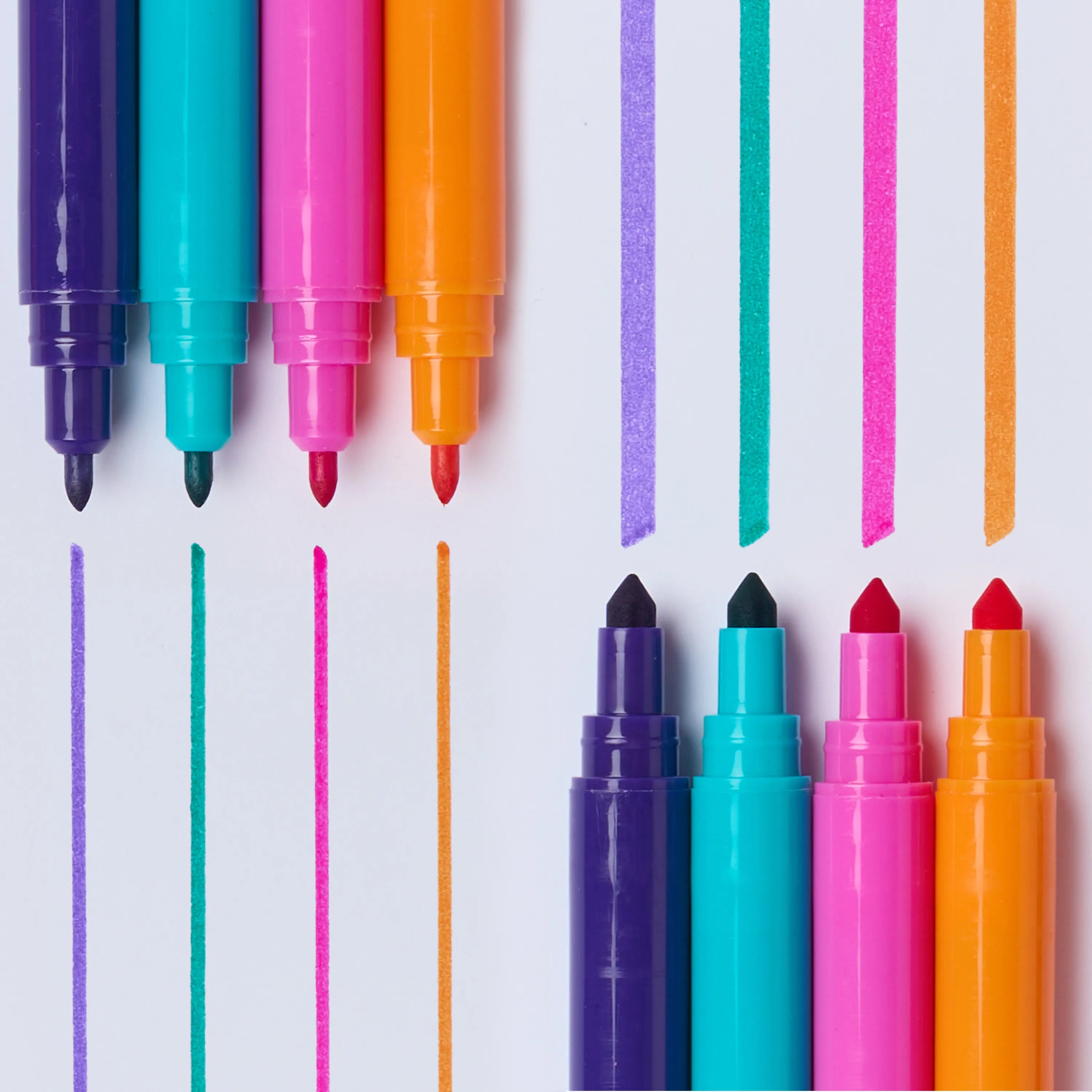 OMY Super Clean 16 washable dual-tip markers detail – top view of brush and fine tips in purple, teal, hot pink, orange and red with color stroke lines on white background