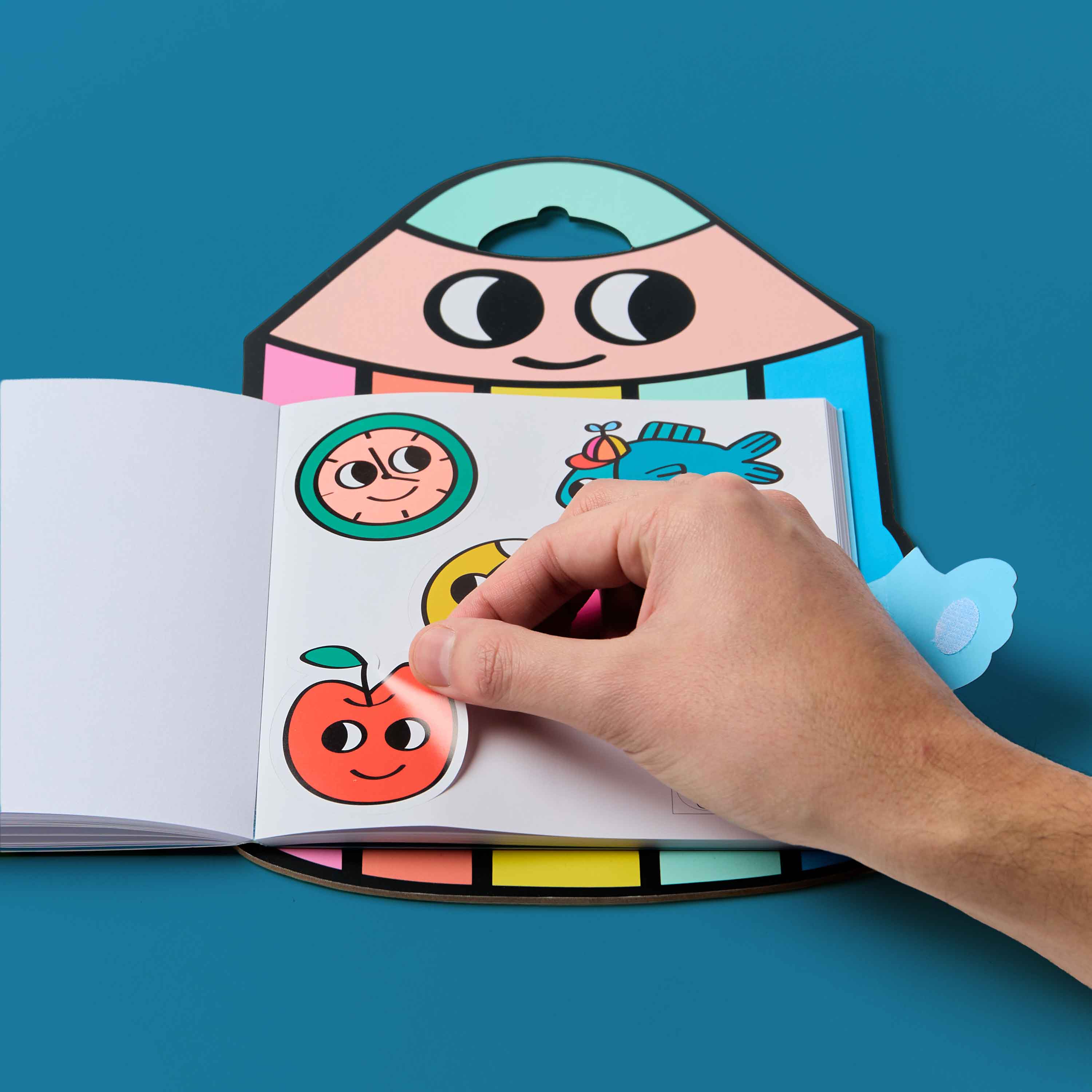 Hand interacting with a colorful Montessori Stickers book OMY featuring cartoon characters on a blue background