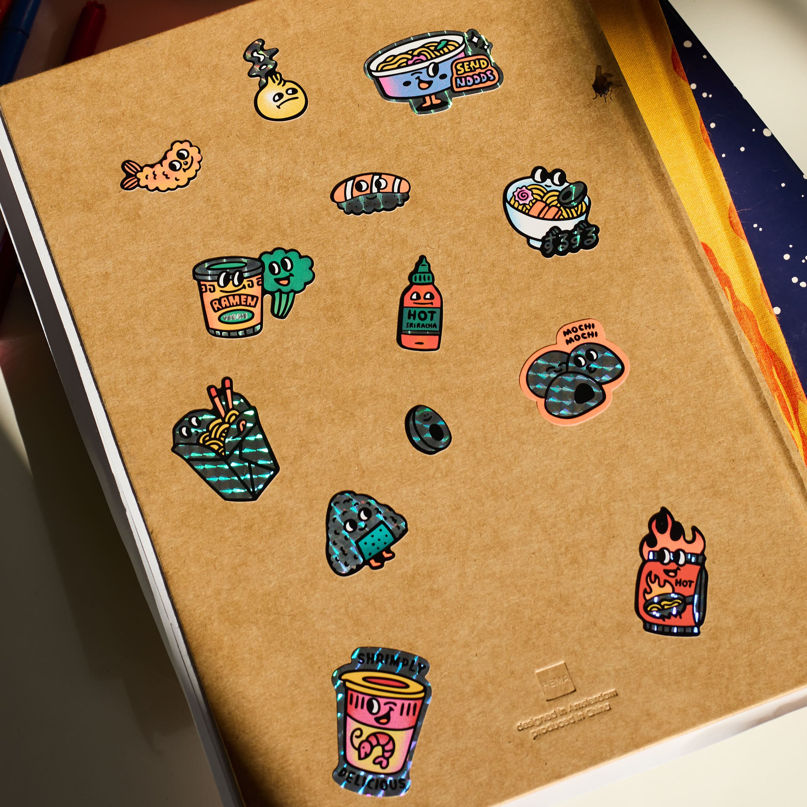 Notebook with colorful stickers  big kitty OMY on a wooden surface