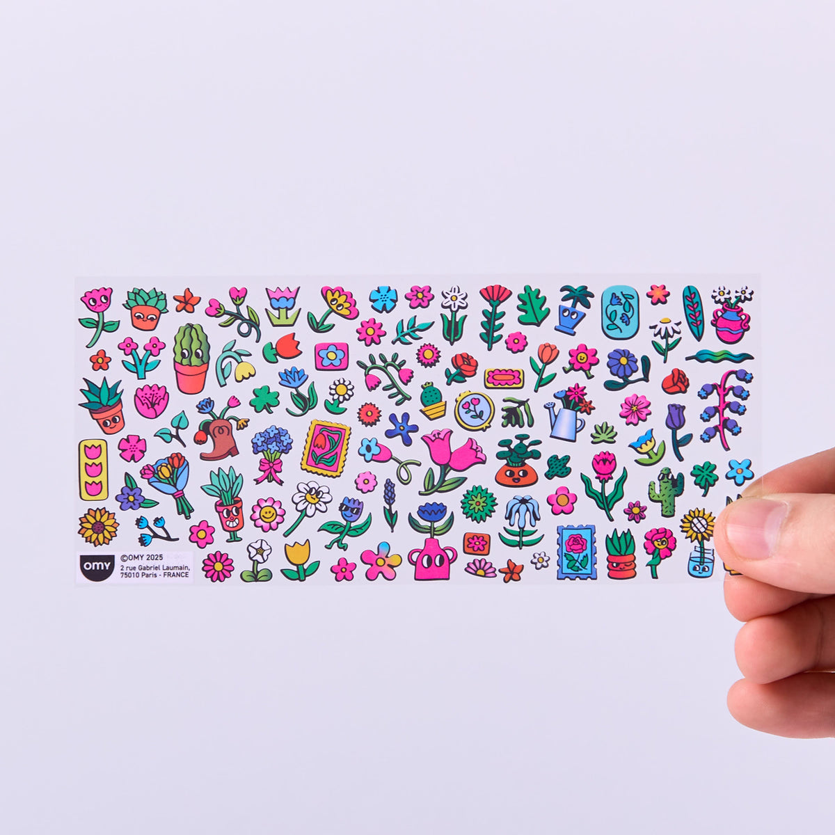 Collection of colorful stickers OMY on a white card held by a hand against a light purple background