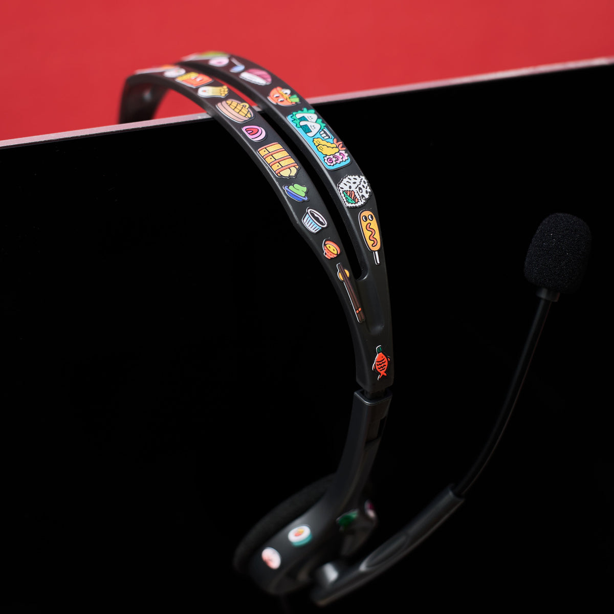 Headset with colorful fabulous stickers on a black surface against a red background