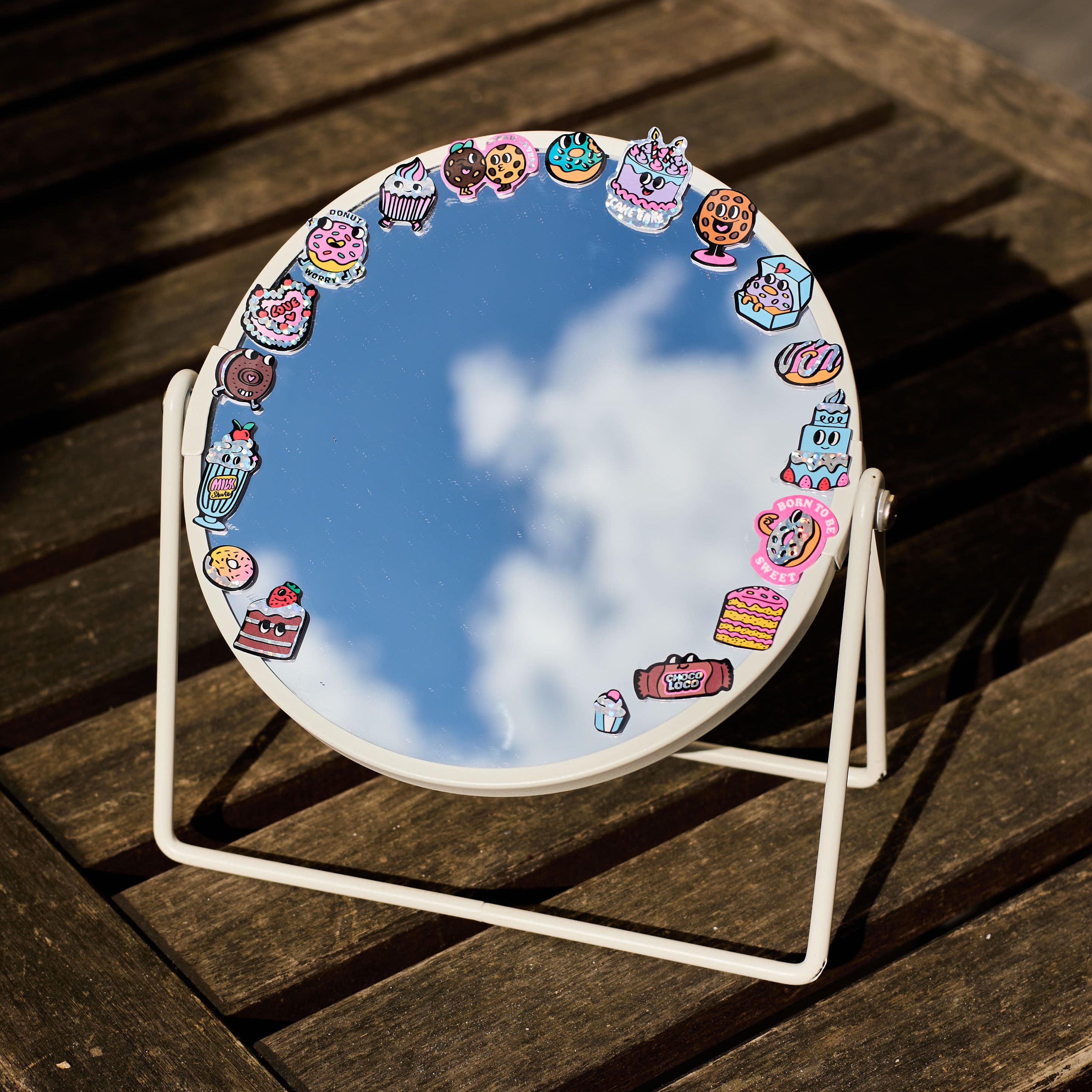Round mirror with decorative fabulous stickers on a wooden surface