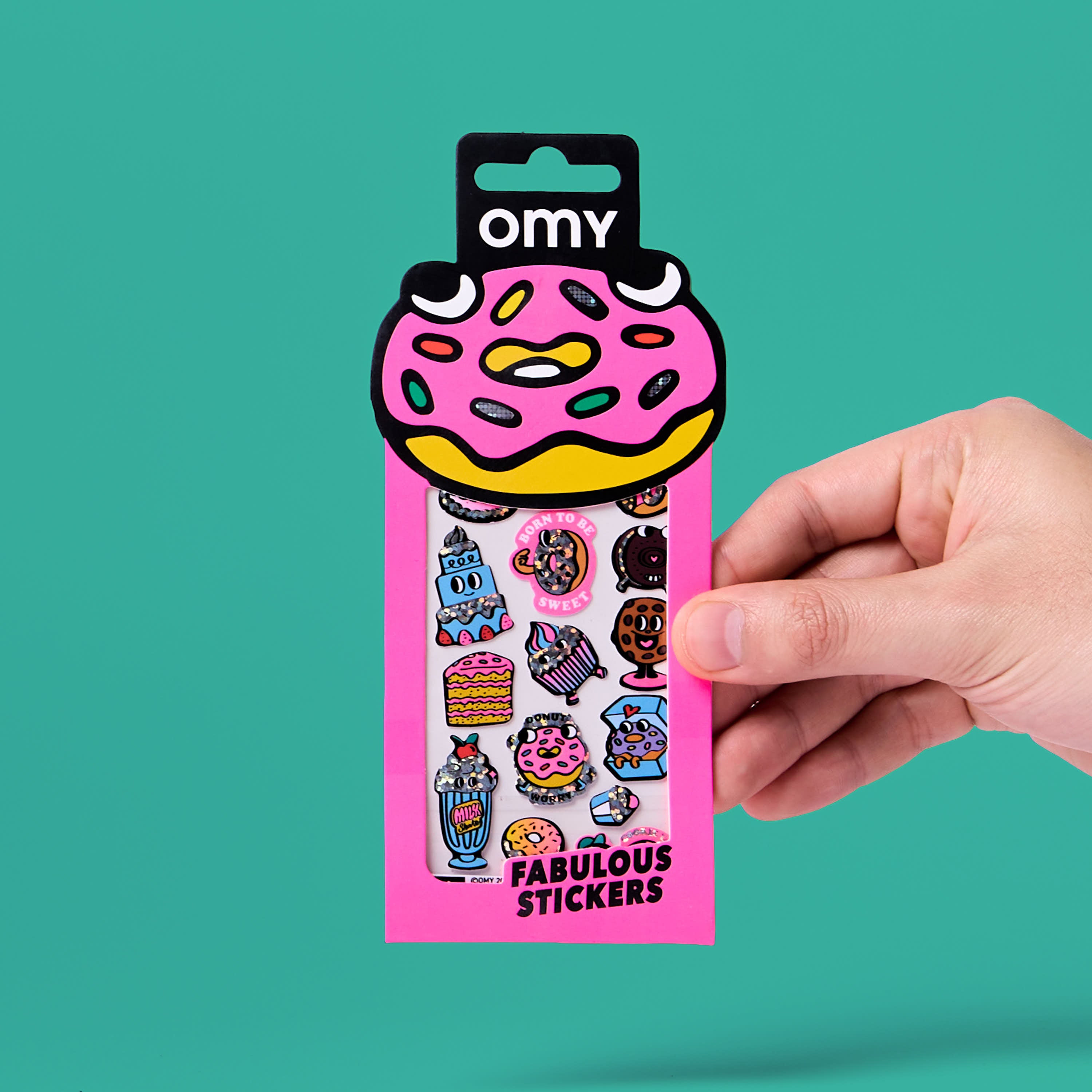 Pack of stickers donuts iconic OMY , held by a hand against a teal background.