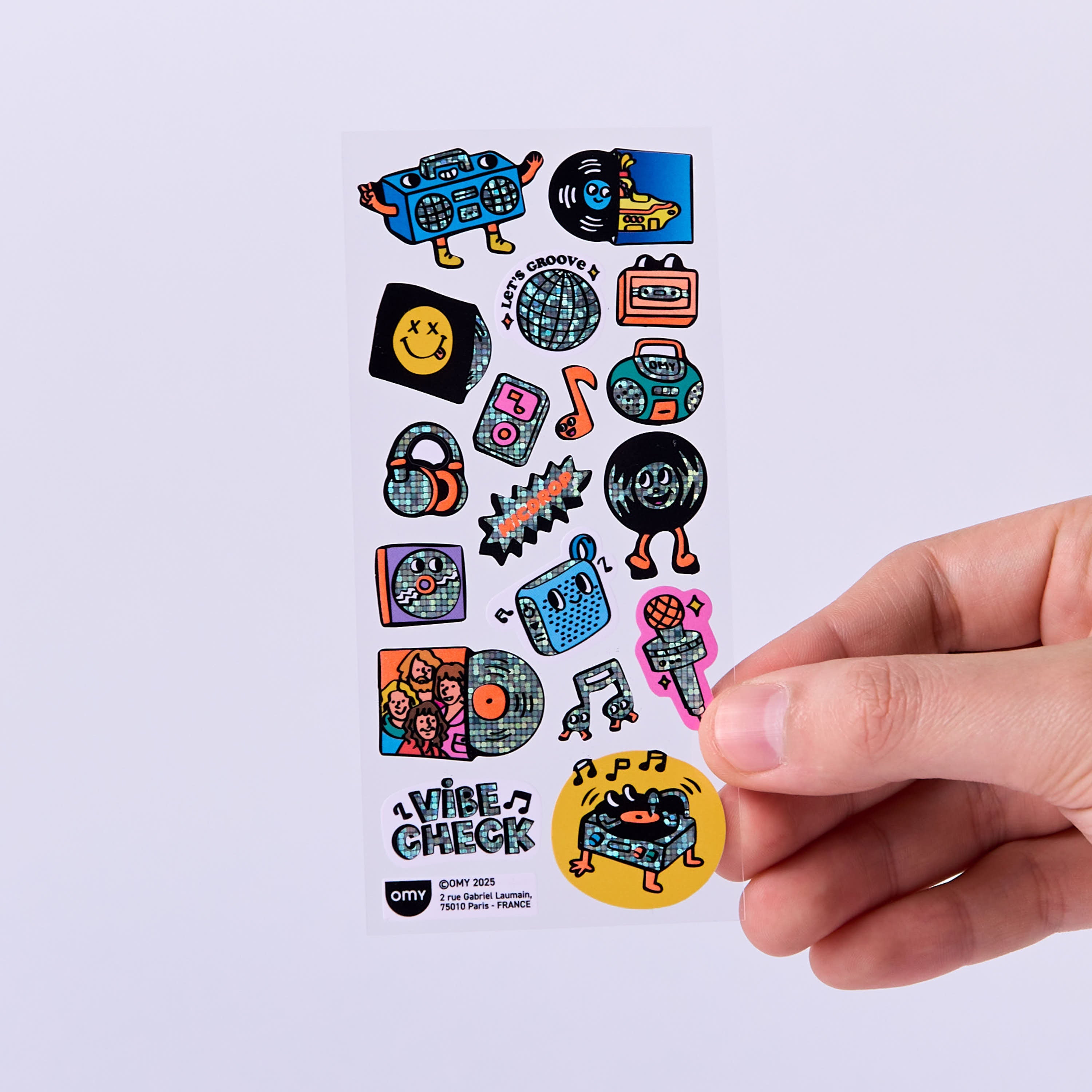 Sheet of colorful stickers music OMY design held by a hand on a light purple background