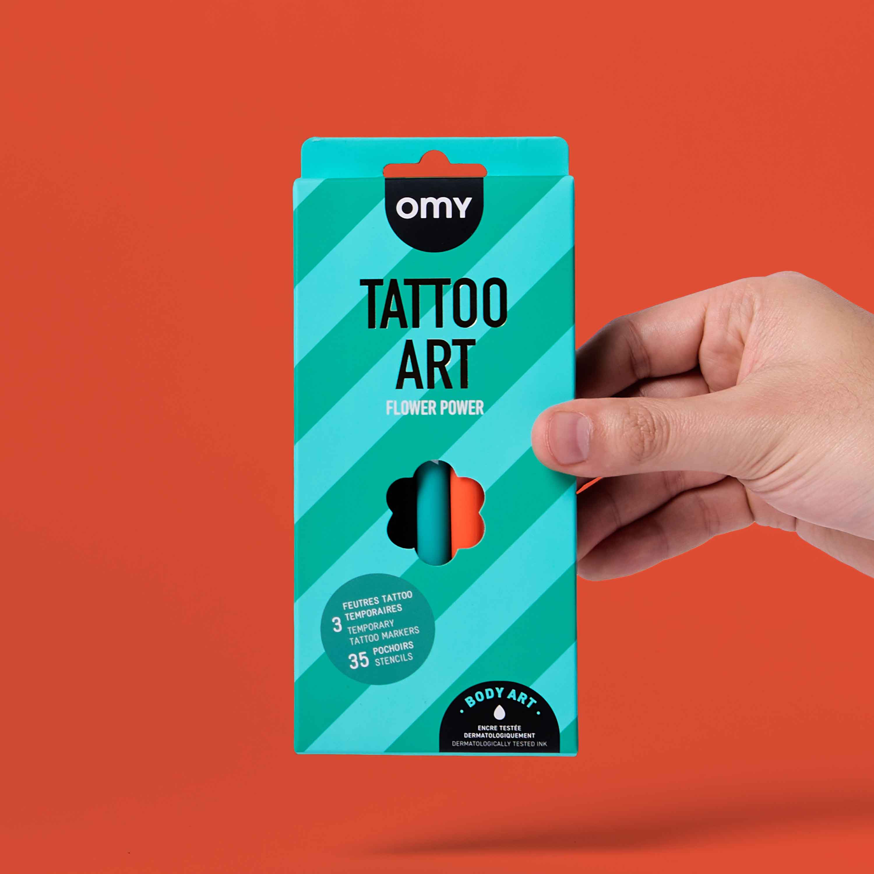 OMY Tattoo Art Flower Power temporary tattoo markers kit packaging held in hand on orange background